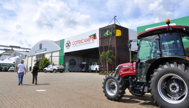 Vista do pavilhão da Cotricampo, na ExpoAgro 2025, com estandes, maquinário agrícola e público circulando pelo evento.