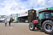 Vista do pavilhão da Cotricampo, na ExpoAgro 2025, com estandes, maquinário agrícola e público circulando pelo evento.